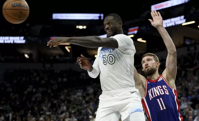 Minnesota Timberwolves forward Julius Randle (30) passes the ball while Sacramento Kings forward Domantas Sabonis (11) defends during the second half of an NBA basketball game, Wednesday, Nov. 27, 2024, in Minneapolis. (AP Photo/Ellen Schmidt)