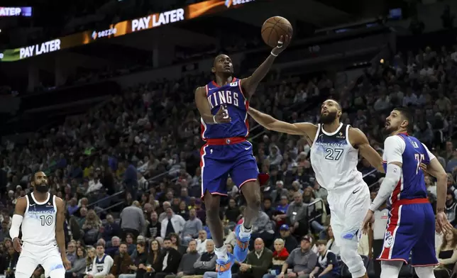 Sacramento Kings guard De'Aaron Fox (5) elevates to shoot against Minnesota Timberwolves center Rudy Gobert (27) while Kings center Alex Len, right, looks on during the first half of an NBA basketball game, Wednesday, Nov. 27, 2024, in Minneapolis. (AP Photo/Ellen Schmidt)