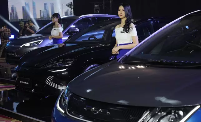 FILE - Models stand near BYD electric cars on display, from left, Atto 3, Seal and Dolphin, during a launch event in Jakarta, Indonesia, on Jan. 18, 2024. (AP Photo/Achmad Ibrahim, File)