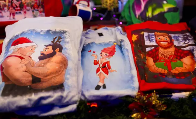 Shirts designed by artist Paul Middleton displayed in a shop at the LGBTQ+ Christmas market "Christmas Avenue" at Nollendorfplatz the for in Berlin, Germany, Monday, Nov. 25, 2024. (AP Photo/Markus Schreiber)