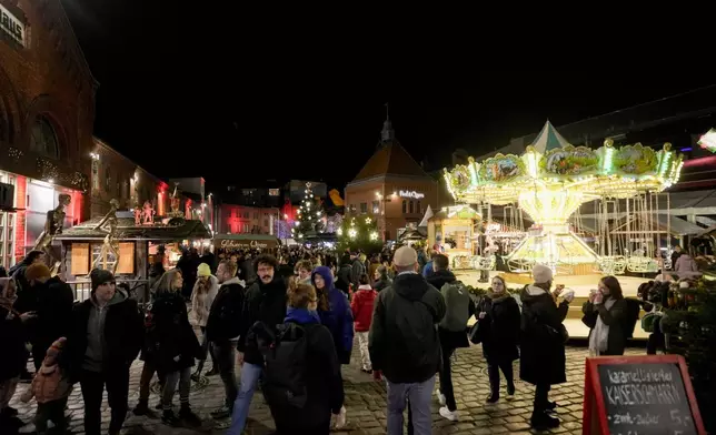 People visit the "Lucia" Christmas Market at the district Prenzlauer Berg in Berlin, Germany, Monday, Nov. 25, 2024. (AP Photo/Markus Schreiber)