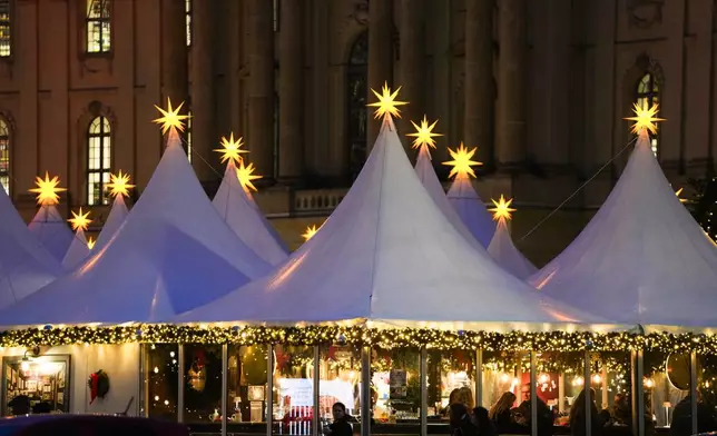 Christmas stars illuminate the top of the tents of the Christmas market at Bebelplatz in the city center of Berlin, Germany, Monday, Nov. 25, 2024. (AP Photo/Markus Schreiber)