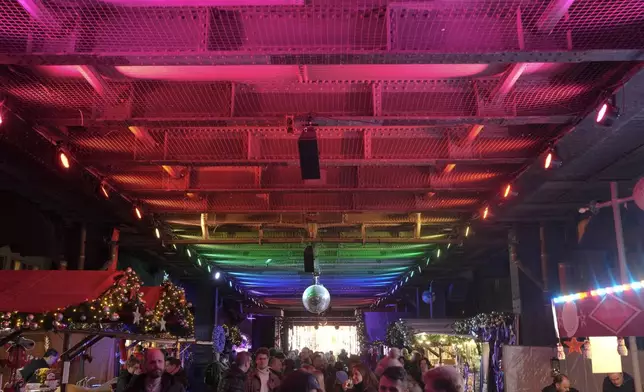 People visit the LGBTQ+ Christmas market "Christmas Avenue" under the tracks of the city train U-Bahn at Nollendorfplatz in Berlin, Germany, Monday, Nov. 25, 2024. (AP Photo/Markus Schreiber)