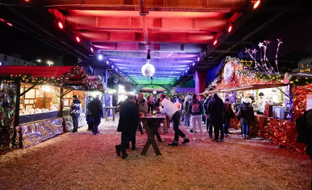 People visits the LGBTQ+ Christmas market "Christmas Avenue" under the tracks of the city train U-Bahn at Nollendorfplatz in Berlin, Germany, Monday, Nov. 25, 2024. (AP Photo/Markus Schreiber)