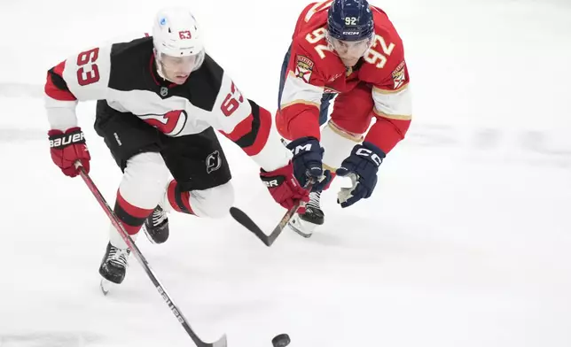 New Jersey Devils left wing Jesper Bratt (63) and Florida Panthers left wing Tomas Nosek (92) battle for the puck during the first period of an NHL hockey game, Thursday, Nov. 14, 2024, in Sunrise, Fla. (AP Photo/Wilfredo Lee)