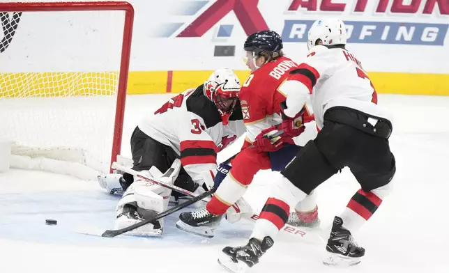 Florida Panthers center Jesper Boqvist, center, scores against New Jersey Devils goaltender Jake Allen (34) and defenseman Dougie Hamilton (7) during the first period of an NHL hockey game, Thursday, Nov. 14, 2024, in Sunrise, Fla. (AP Photo/Wilfredo Lee)