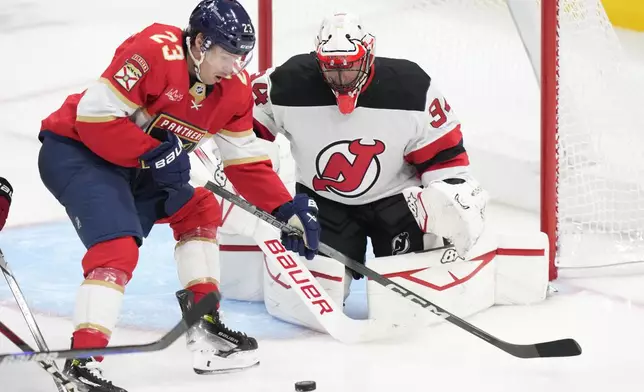 Florida Panthers center Carter Verhaeghe (23) is unable to take a shot at New Jersey Devils goaltender Jake Allen (34) during the second period of an NHL hockey game, Thursday, Nov. 14, 2024, in Sunrise, Fla. (AP Photo/Wilfredo Lee)