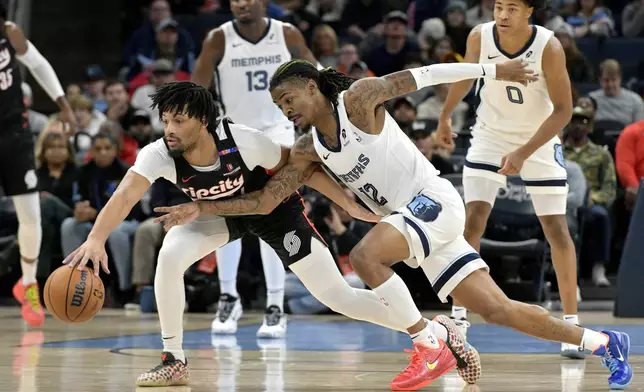 Portland Trail Blazers guard Shaedon Sharpe, left, and Memphis Grizzlies guard Ja Morant (12) struggle for control of the ball in the first half of an NBA basketball game Monday, Nov. 25, 2024, in Memphis, Tenn. (AP Photo/Brandon Dill)