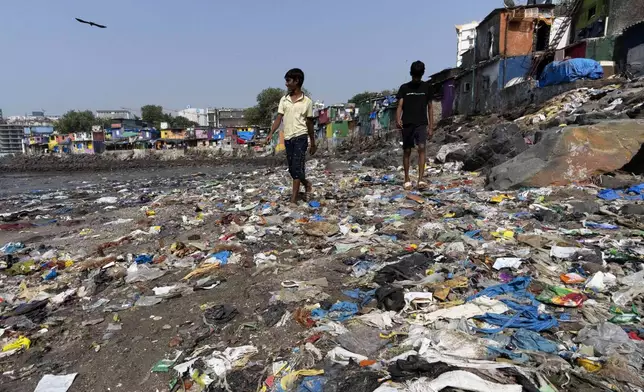 People walk past plastic waste on Badhwar Park beach by the Arabian Sea coast in Mumbai, India, Tuesday, Nov. 26, 2024.(AP Photo/Rajanish Kakade)