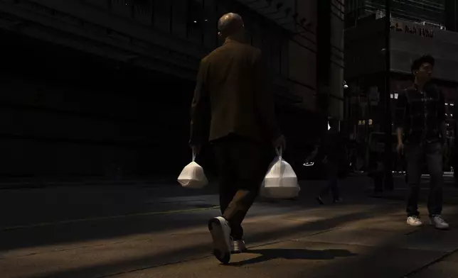 FILE- A pedestrian carries takeaway food plastic bags in Hong Kong, Wednesday, March 13, 2024. (AP Photo/Louise Delmotte, File)