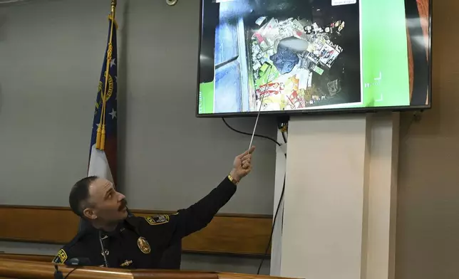 Athens-Clarke County police officer Zachary Davis points out the jacket he collected from a dumpster on photograph as he testifies on the witness stand during a trial of Jose Ibarra, accused of killing a Georgia nursing student earlier this year, at Athens-Clarke County Superior Court, Friday, Nov. 15, 2024, in Athens, Ga. (Hyosub Shin/Atlanta Journal-Constitution via AP, Pool)