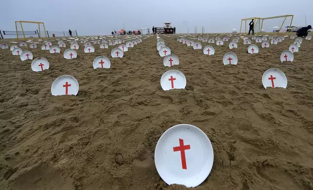 Plates marked with crosses, symbolizing people suffering from hunger worldwide, are displayed at Copacabana Beach during a protest aimed at drawing the attention of leaders attending the upcoming G20 summit in Rio de Janeiro, Saturday, Nov. 16, 2024. (AP Photo/Dhavid Normando)