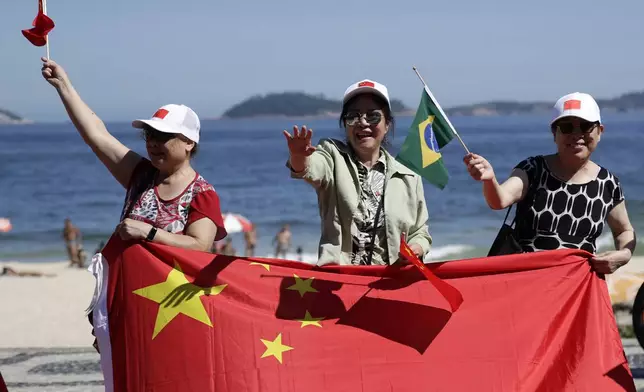 People wave Chinese and Brazilian flags as they wait for China's President Xi Jinping for him to drive past Leblon beach to his hotel during the G20 summit in Rio de Janeiro, Monday, Nov. 18, 2024. (AP Photo/Bruna Prado)