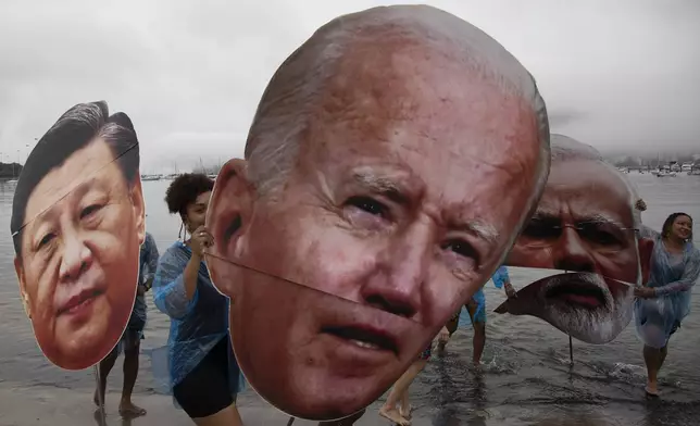 Activists from a Brazilian Indigenous movement hold cutouts of Chinese President Xi Jinping, from left, President Joe Biden and Indian Prime Minister Narendra Modi, during a protest aimed at drawing the attention on the global climate crisis to leaders attending the upcoming G20 Summit, at Botafogo Beach in Rio de Janeiro, Saturday, Nov. 16, 2024. (AP Photo/Bruna Prado)