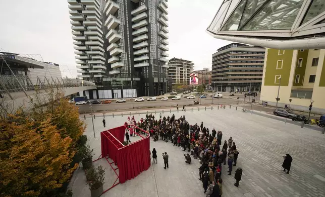 People participate in the unveiling of a red bench on the occasion of the International Day for the Elimination of Violence against Women, in Milan, Italy, Monday, Nov. 25, 2024. (AP Photo/Luca Bruno)