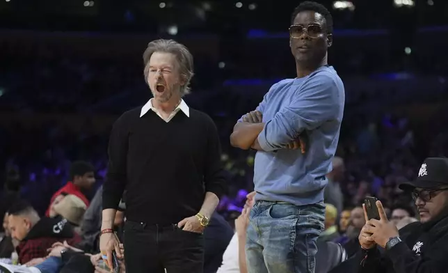 Comedians Chris Rock, right, and David Spade stand near their seats during a break in the first half of an NBA basketball game between the Los Angeles Lakers and the Memphis Grizzlies, Wednesday, Nov. 13, 2024, in Los Angeles. (AP Photo/Marcio Jose Sanchez)