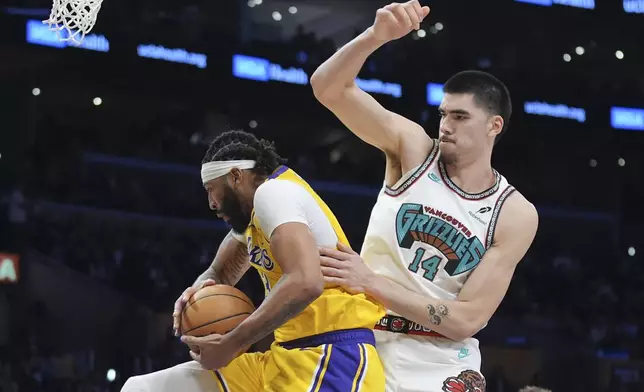 Los Angeles Lakers forward Anthony Davis, left, grabs a rebound over Memphis Grizzlies center Zach Edey (14) during the first half of an NBA basketball game Wednesday, Nov. 13, 2024, in Los Angeles. (AP Photo/Marcio Jose Sanchez)