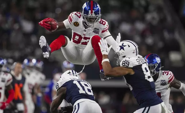 New York Giants wide receiver Ihmir Smith-Marsette (87) leaps over Dallas Cowboys' Damone Clark (18) and Brevyn Spann-Ford (89) on a punt return during the first half of an NFL football game in Arlington, Texas, Thursday, Nov. 28, 2024. (AP Photo/Tony Gutierrez)