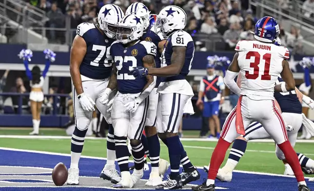 Dallas Cowboys running back Rico Dowdle (23) is surrounded by teammates after scoring a touchdown against the New York Giants during the second half of an NFL football game in Arlington, Texas, Thursday, Nov. 28, 2024. (AP Photo/Jerome Miron)