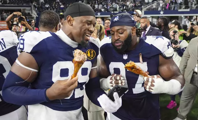 Dallas Cowboys defensive end Chauncey Golston (99) and defensive tackle Osa Odighizuwa (97) eat a turkey leg following an NFL football game against the New York Giants in Arlington, Texas, Thursday, Nov. 28, 2024. (AP Photo/Tony Gutierrez)