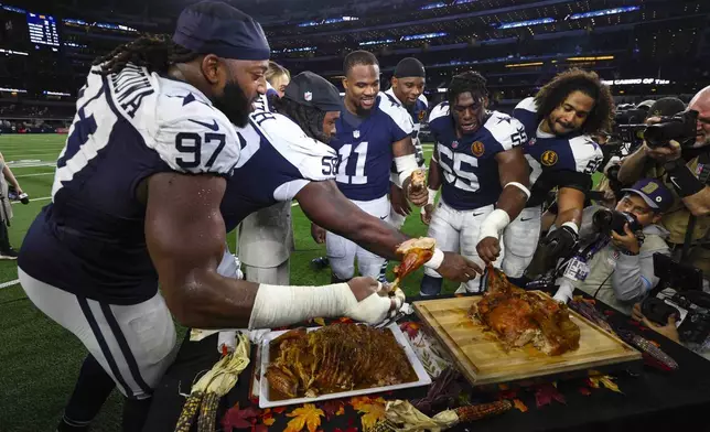 Dallas Cowboy players grab some turkey following an NFL football game against the New York Giants in Arlington, Texas, Thursday, Nov. 28, 2024. (AP Photo/Richard Roriguez)