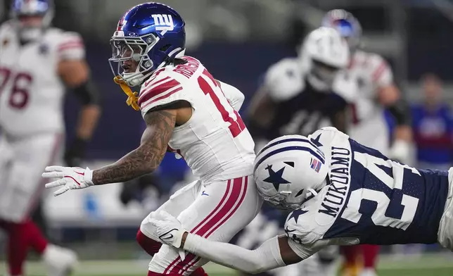 Dallas Cowboys safety Israel Mukuamu (24) tackles New York Giants wide receiver Wan'Dale Robinson (17) after a catch during the second half of an NFL football game in Arlington, Texas, Thursday, Nov. 28, 2024. (AP Photo/Tony Gutierrez)