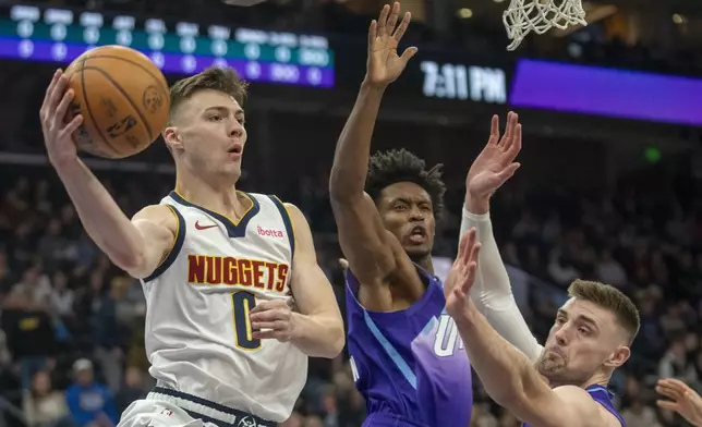 Denver Nuggets guard Christian Braun looks to pass as Utah Jazz guard Collin Sexton, middle, and Utah Jazz forward Drew Eubanks, right, defend during the first half of an NBA basketball game Wednesday, Nov. 27, 2024, in Salt Lake City. (AP Photo/Rick Egan)