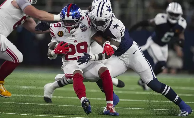 New York Giants running back Tyrone Tracy Jr. (29) is tackled by Dallas Cowboys linebacker DeMarvion Overshown (13) during the first half of an NFL football game in Arlington, Texas, Thursday, Nov. 28, 2024. (AP Photo/Tony Gutierrez)