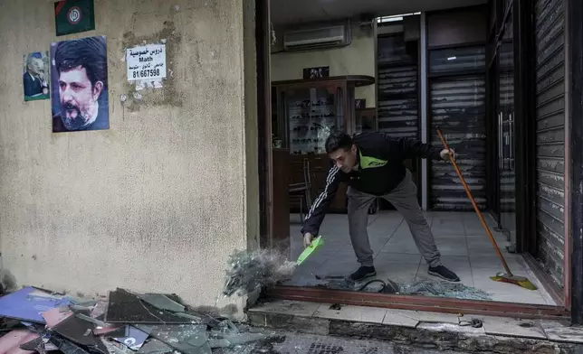 A man clears broken glass from his damaged shop near a building hit on Monday evening by an Israeli airstrike in central Beirut, Lebanon, Tuesday, Nov. 19, 2024. (AP Photo/Bilal Hussein)