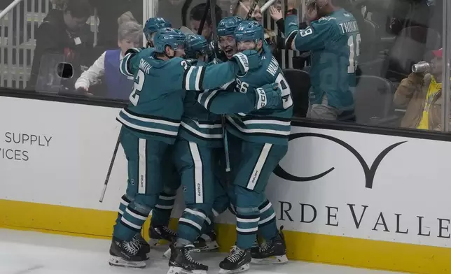 San Jose Sharks center Macklin Celebrini, middle, is congratulated by teammates after scoring the winning goal during overtime of an NHL hockey game against the Detroit Red Wings in San Jose, Calif., Monday, Nov. 18, 2024. (AP Photo/Jeff Chiu)