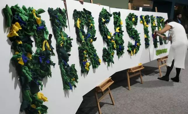 An activist works on a display that reads in Portuguese persistir, that translates to persist, during the COP29 U.N. Climate SuRafiq Maqbool Nov. 22, 2024, in Baku, Azerbaijan. (AP Photo/Rafiq Maqbool)