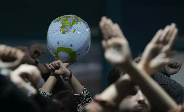 Activists hold an inflatable globe as they demonstrate in silence protesting a draft of a proposed deal for curbing climate change at the COP29 U.N. Climate Summit, Friday, Nov. 22, 2024, in Baku, Azerbaijan. (AP Photo/Rafiq Maqbool)