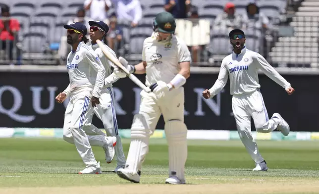 India's Virat Kohli, right, celebrates the wicket of Australia's Steve Smith, center, who leaves the field after losing his wicket on the fourth day of the first cricket test between Australia and India in Perth, Australia, Monday, Nov. 25, 2024. (AP Photo/Trevor Collens)