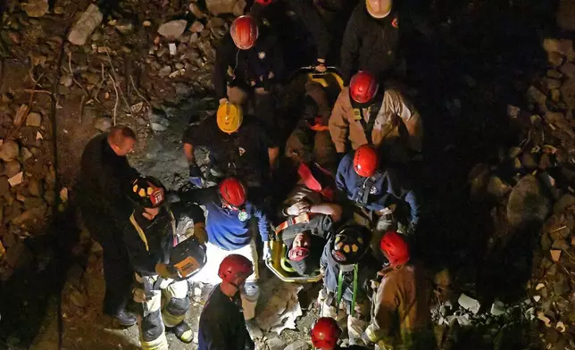 Members of the Louisville Metro Fire Department carry an injured worker to safety after being trapped under rubble at construction site in Louisville, Ky., Thursday, Nov. 14, 2024. (AP Photo/Timothy D. Easley)