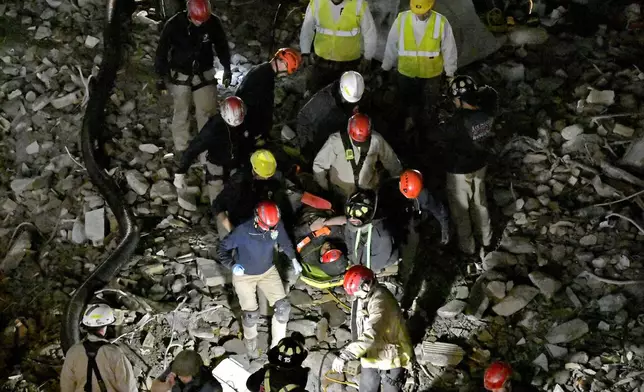 Members of the Louisville Metro Fire Department carry an injured worker to safety after being trapped under rubble at construction site in Louisville, Ky., Thursday, Nov. 14, 2024. (AP Photo/Timothy D. Easley)