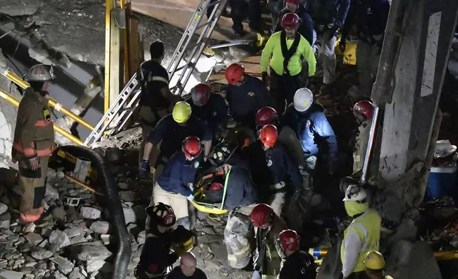 Members of the Louisville Metro Fire Department carry an injured worker to safety after being trapped under rubble at construction site in Louisville, Ky., Thursday, Nov. 14, 2024. (AP Photo/Timothy D. Easley)