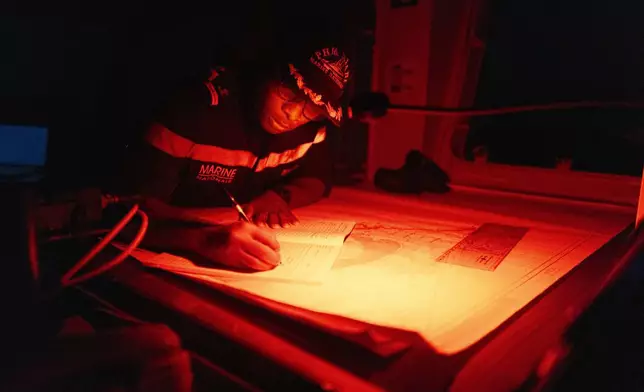 A Senegalese sailor fills in the logbook of the offshore patrol vessel Niani during a mission to search for migrant boats near the coast of Dakar, Senegal, Saturday, Nov.16, 2024. (AP Photo/Sylvain Cherkaoui)