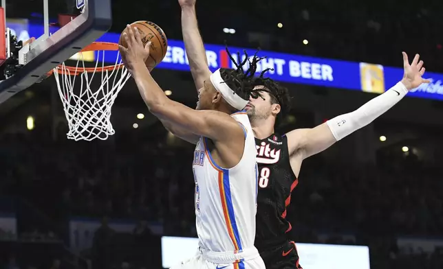 Oklahoma CIty Thunder forward Ousmane Dieng, left, shoots around Portland Trail Blazers forward Deni Avdija, right, during the second half of an NBA basketball game, Wednesday, Nov. 20, 2024, in Oklahoma City. (AP Photo/Kyle Phillips)