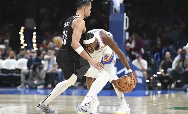 Oklahoma CIty Thunder guard Shai Gilgeous-Alexander, right, looks for an opening past Portland Trail Blazers forward Toumani Camara, left, during the second half of an NBA basketball game, Wednesday, Nov. 20, 2024, in Oklahoma City. (AP Photo/Kyle Phillips)