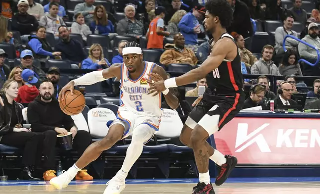 Oklahoma CIty Thunder guard Shai Gilgeous-Alexander, left, drives past Portland Trail Blazers guard Scoot Henderson, right, during the second half of an NBA basketball game, Wednesday, Nov. 20, 2024, in Oklahoma City. (AP Photo/Kyle Phillips)