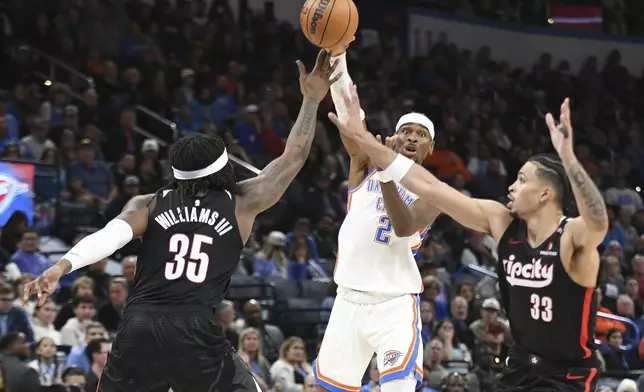 Oklahoma CIty Thunder guard Shai Gilgeous-Alexander (2) passes over Portland Trail Blazers center Robert Williams III (35) and forward Toumani Camara (33) during the second half of an NBA basketball game, Wednesday, Nov. 20, 2024, in Oklahoma City. (AP Photo/Kyle Phillips)