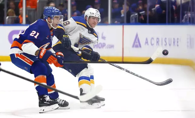 St. Louis Blues defenseman Scott Perunovich (48) passed the puck against New York Islanders center Kyle Palmieri (21) during the first period of an NHL hockey game, Saturday, Nov. 23, 2024, in New York. (AP Photo/Noah K. Murray)