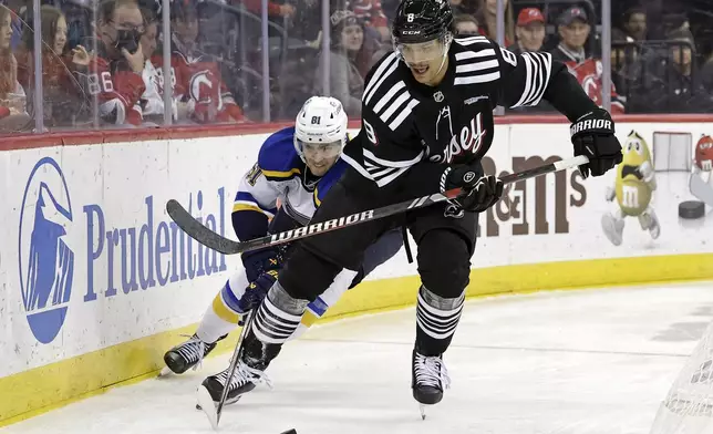 New Jersey Devils defenseman Johnathan Kovacevic (8) battles for the puck with St. Louis Blues center Dylan Holloway during the third period of an NHL hockey game Wednesday, Nov. 27, 2024, in Newark, N.J. St. Louis won 3-0. (AP Photo/Adam Hunger)