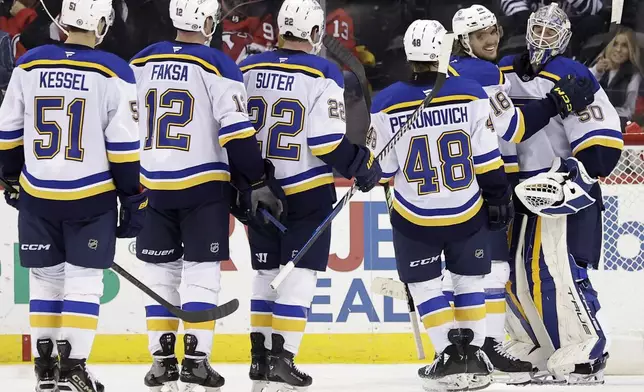 St. Louis Blues goaltender Jordan Binnington is congratulated by Robert Thomas (18) after the Blues defeated the New Jersey Devils 3-0 in an NHL hockey game Wednesday, Nov. 27, 2024, in Newark, N.J. (AP Photo/Adam Hunger)