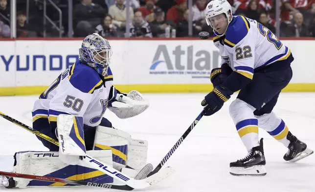 St. Louis Blues goaltender Jordan Binnington and Ryan Suter (22) watch the puck go past during the second period of an NHL hockey game against the New Jersey Devils Wednesday, Nov. 27, 2024, in Newark, N.J. (AP Photo/Adam Hunger)