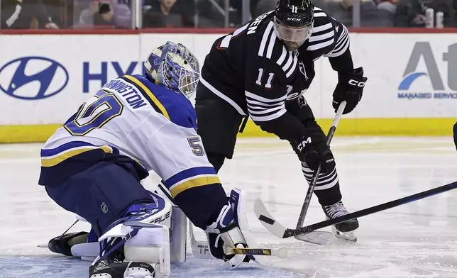 St. Louis Blues goaltender Jordan Binnington stops a shot in front of New Jersey Devils right wing Stefan Noesen (11) during the second period of an NHL hockey game, Wednesday, Nov. 27, 2024, in Newark, N.J. (AP Photo/Adam Hunger)