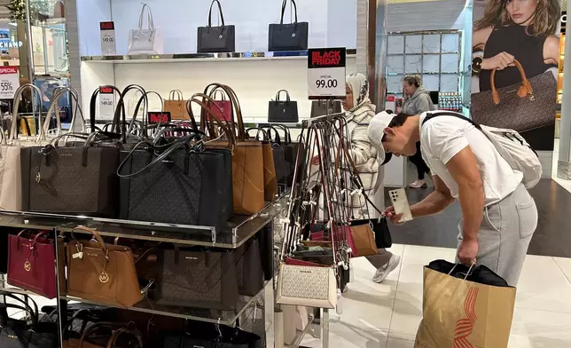 A shopper looks at handbags at Macy's department store on Sunday, Nov. 24, 2024, in New York. (AP Photo/Anne D'Innocenzio)