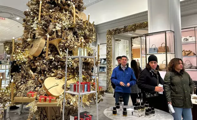 Shoppers pass a Christmas tree at the Bergdorf Goodman store on Sunday, Nov. 24, 2024, in New York. (AP Photo/Anne D'Innocenzio)