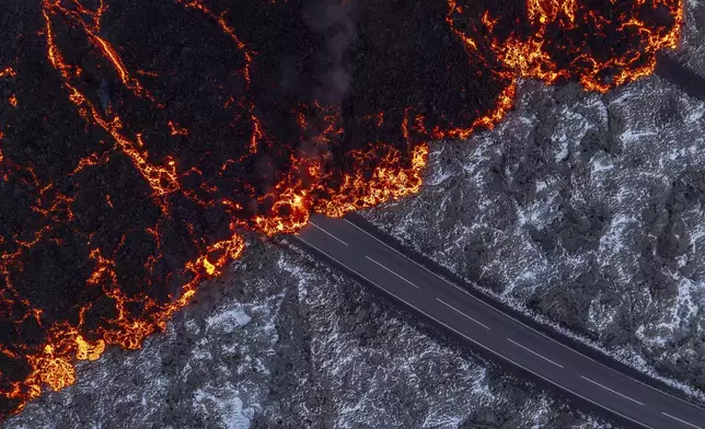 Molten lava flows on the road to the Blue Lagoon, Grindavik, after the volcanic eruption that started Wednesday, on the Reykjanes Peninsula in Iceland, Thursday, Nov.21, 2024. (AP Photo/Marco di Marco)