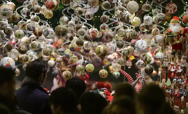 People look at Christmas baubles at the Wiener Chritkindlmarkt in front of Vienna's city hall, one of Vienna's most popular Christmas markets, in Vienna, Austria, Saturday, Nov. 16, 2024. (AP Photo/Christian Bruna)